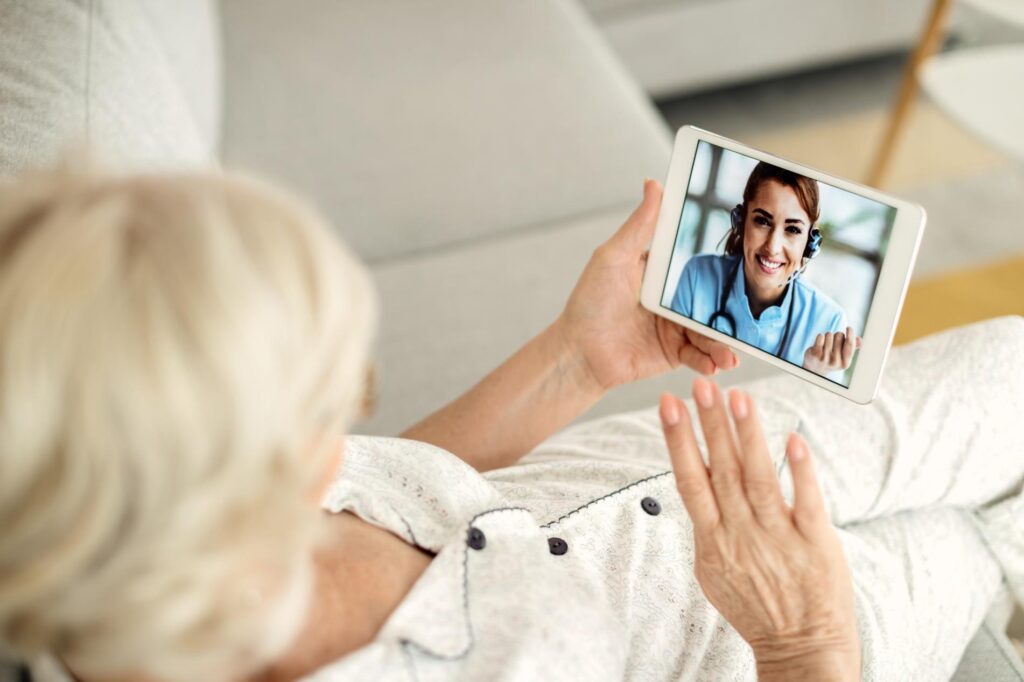 24 uurs Thuiszorg Alicante verzorger communiceert met oudere vrouw op bank op iPad